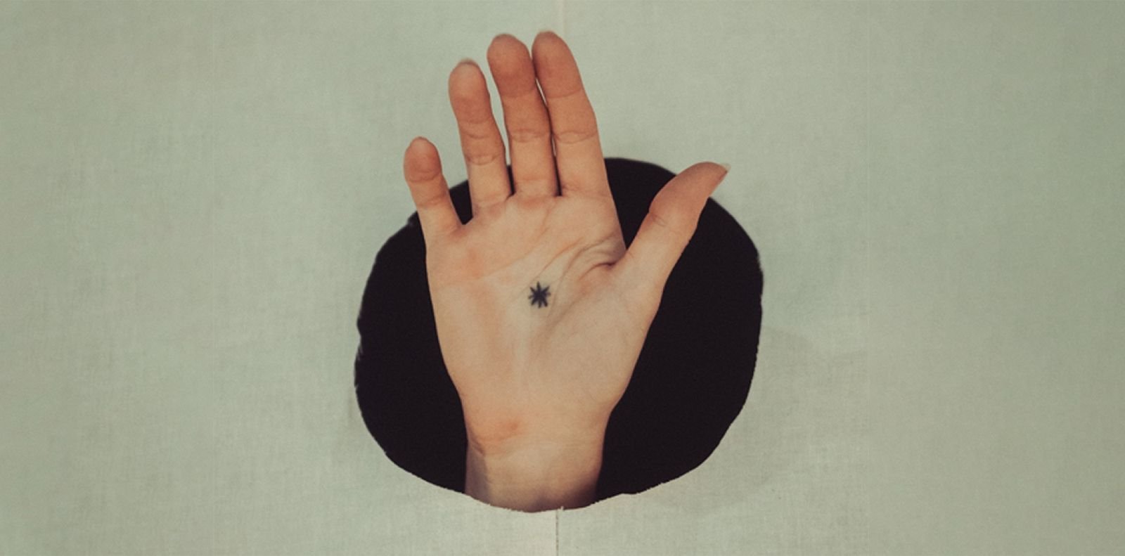 A hand marked with the 809 asterisk reaching through a round opening in a white wall